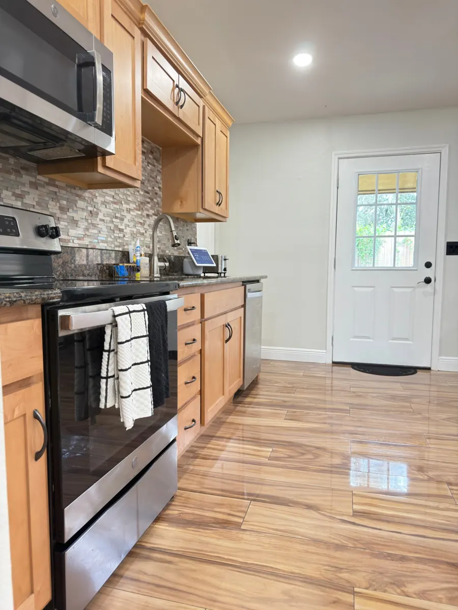 Cocina limpia con gabinetes de madera, electrodomésticos de acero inoxidable y piso brillante después de una limpieza residencial de AD Cleaning Orlando